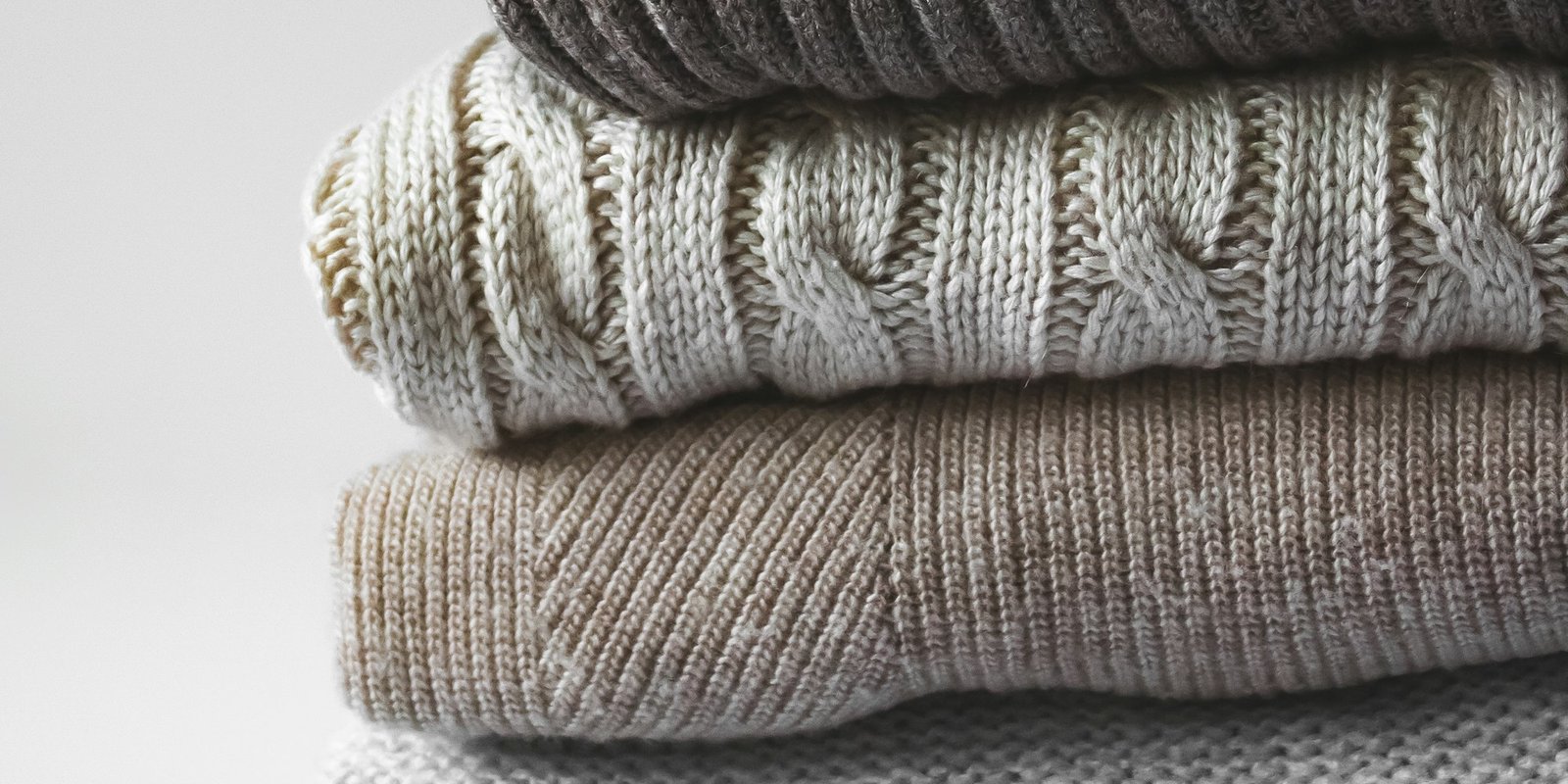 Three folded knitted fabrics stacked and seen edge on, each a different thickness and construction